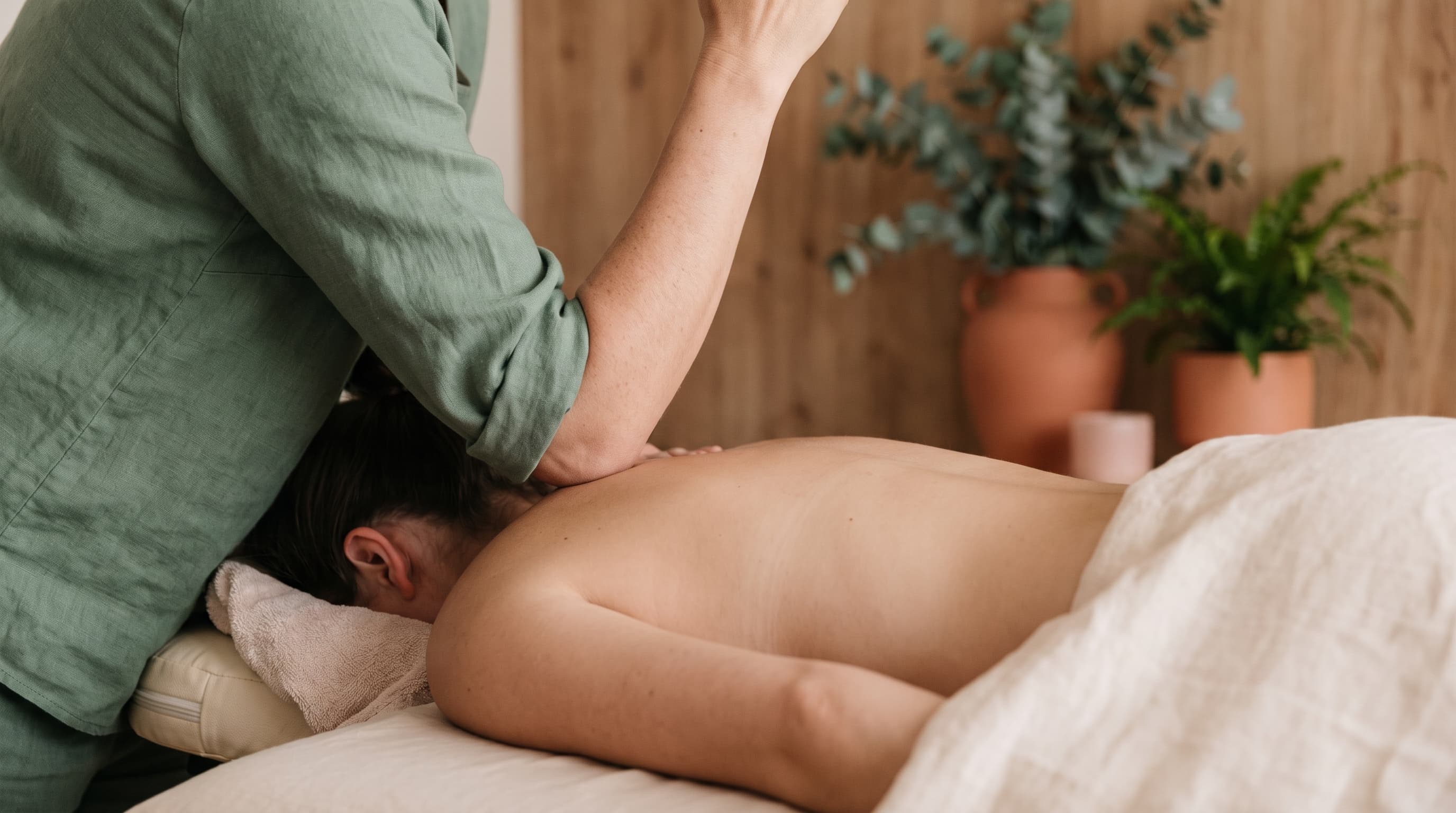 Fern & Soul deep tissue massage in Innaloo — a therapist's forearm working slowly along a relaxed client's upper back on cream linen.