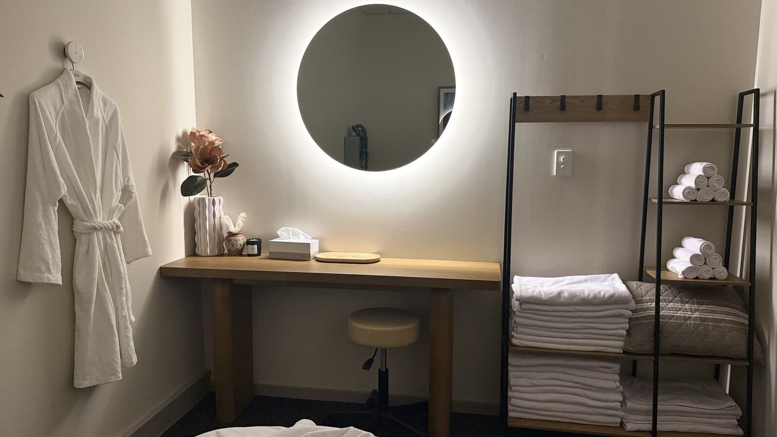 Fern & Soul treatment room in Innaloo, with a waffle robe, backlit round mirror, fresh rolled towels and folded linens