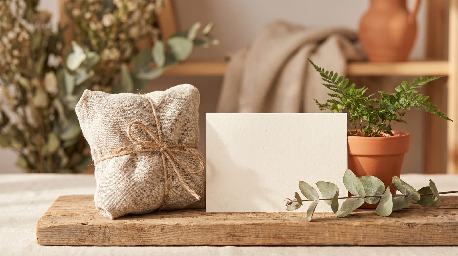 Fern & Soul Father's Day gift ideas in Innaloo, a linen wrapped parcel and a plain cream card on raw timber beside eucalyptus.