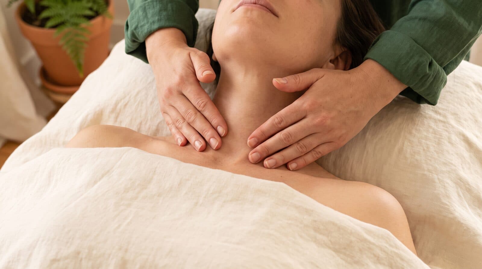 Lymphatic drainage facial at Fern & Soul Innaloo, a therapist's fingertips resting lightly along a relaxed client's jawline.