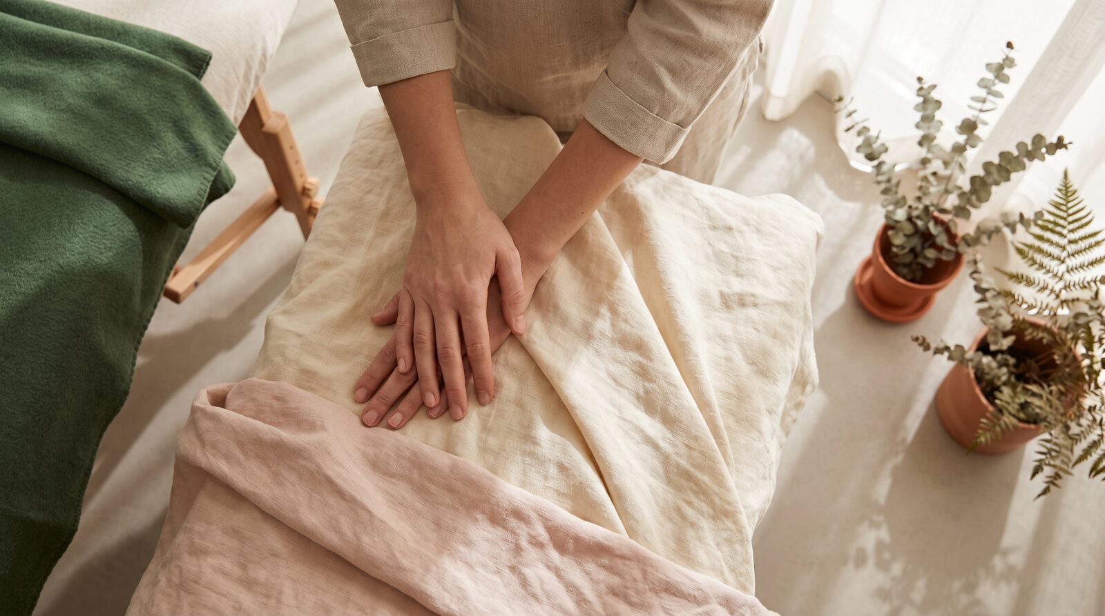 Fern & Soul massage studio in Innaloo, hands resting calmly beside a treatment table with folded linen in warm afternoon light.
