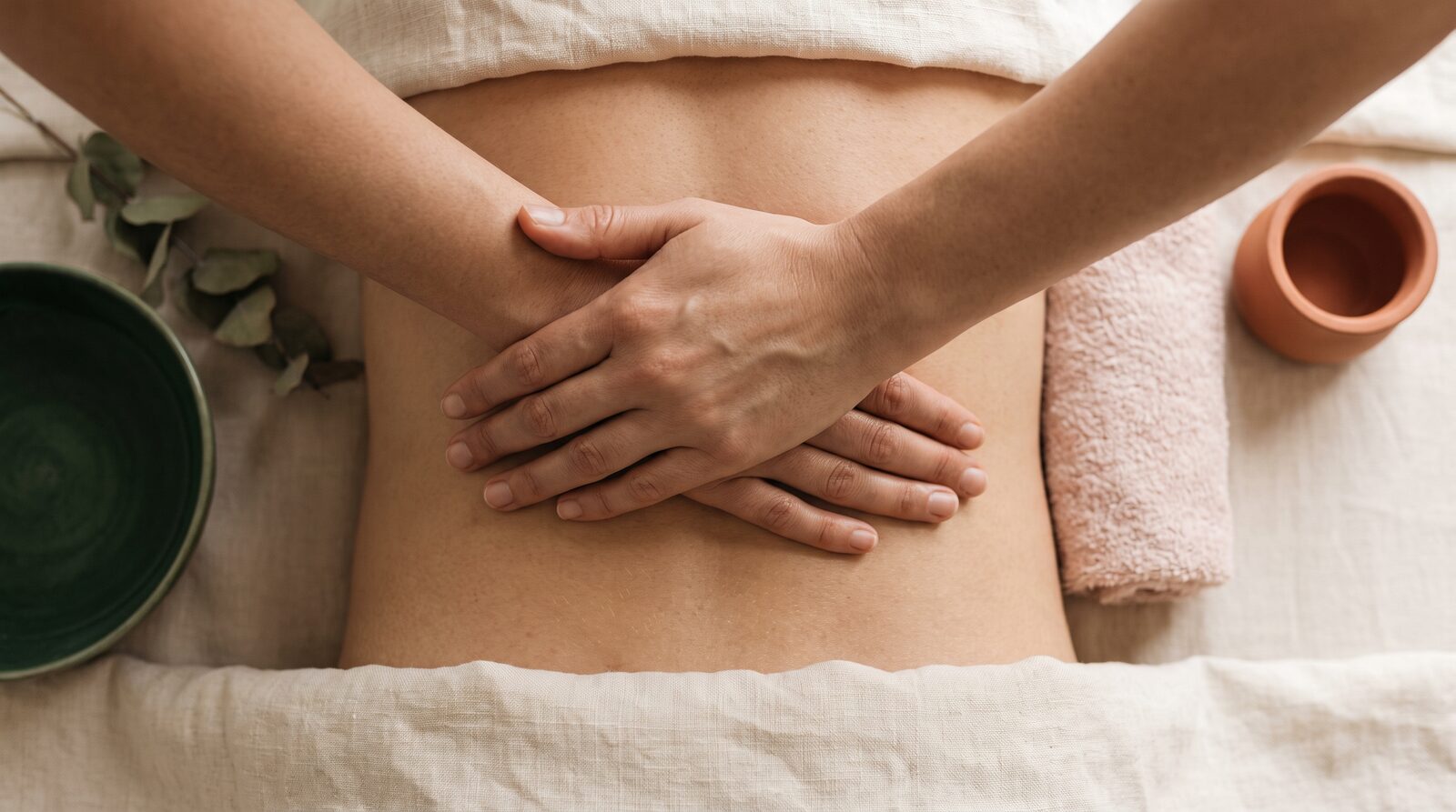 Fern & Soul remedial massage in Innaloo, a therapist's hands resting across a relaxed client's lower back on cream linen.