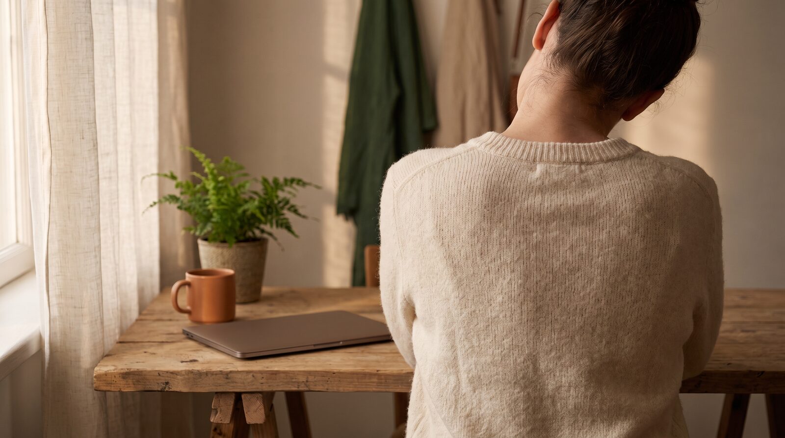 Fern & Soul desk tension relief in Innaloo, a person seen from behind easing their shoulders at a timber desk and laptop.